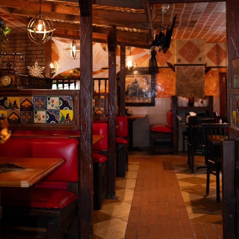 Warmly lit interior of Papa's & Beer, featuring red booths, wooden accents, and decorative Mexican tiles.