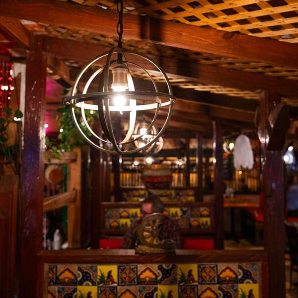 Warmly lit interior of Papa's & Beer, featuring a spherical metal chandelier and colorful Mexican tiles.