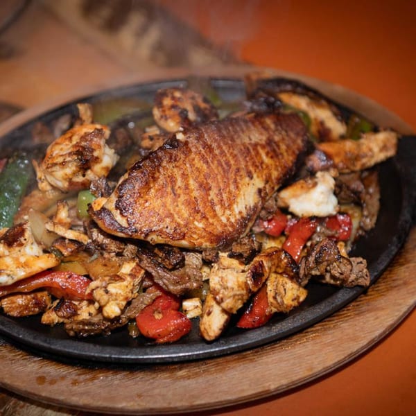 Sizzling Papa's & Beer fajitas with chicken, steak, fish, red peppers, and onions.