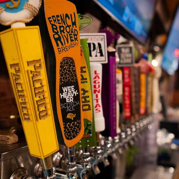 Close-up of a row of beer taps with various brand handles at Papa's & Beer.